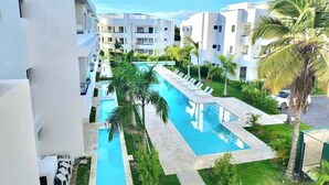 Un hotel modern amb una piscina central, envoltat de vegetació exuberant i palmeres.