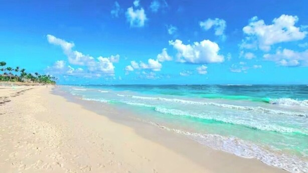 Una platja amb cel blau i aigües tranquil·les.