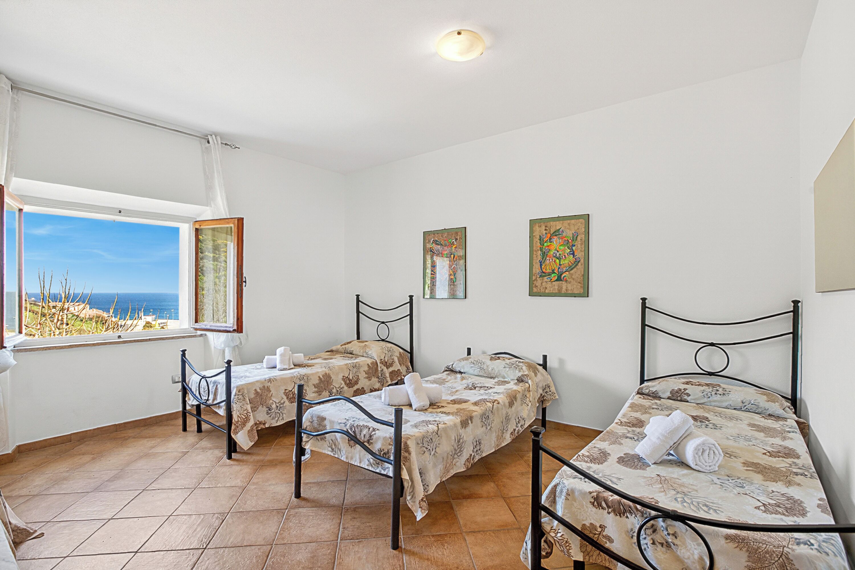 A room with two beds, a window with a view, and artwork on the walls.