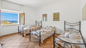A room with two beds, a window with a view, and artwork on the walls.