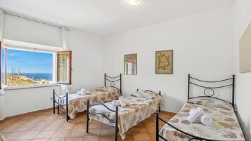 A room with two beds, a window with a view, and artwork on the walls.