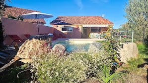 A residential area with a swimming pool, outdoor furniture, and a house with a tiled roof. - Charmante maison avec piscine (Pomport)