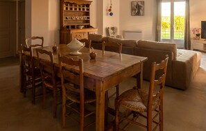 Un coin repas avec une table et des chaises en bois, un canapé et un buffet contenant de la vaisselle.