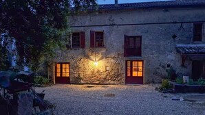 A rustic stone building with two doors and windows, a gravel driveway, and a small garden area. - Belle maison avec piscine (Les Esseintes)