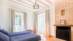A bedroom with a bed, a fireplace, and a view of the outdoors. - Belle maison avec piscine (Les Esseintes)