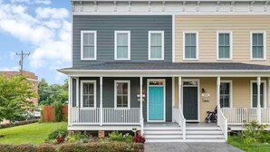 A two-story residential building with a front porch, a blue door, and a mailbox.