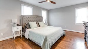 A bedroom with a bed, nightstands, a ceiling fan, and a dresser.