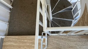 A spiral staircase with white railings and a beige carpeted floor. - Bonomi vacation home 15 meters from the beach (Porto Cesareo)