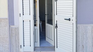 A doorway with a sliding glass door, a small step leading into a room, and a white wall with a textured surface. - Bonomi vacation home 15 meters from the beach (Porto Cesareo)