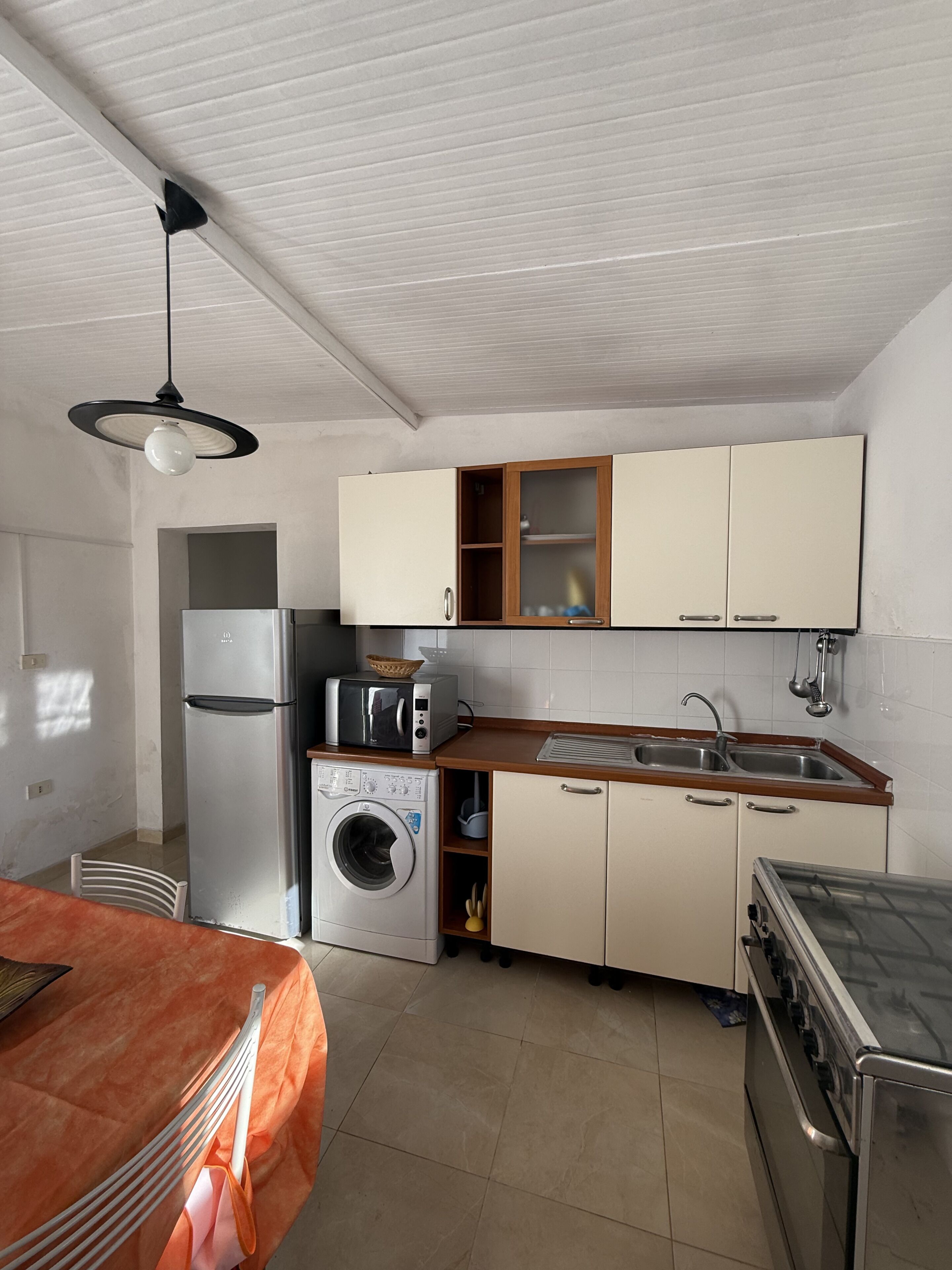 Una cocina compacta con lavadora, estufa, microondas y fregadero.