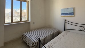 Une pièce avec un lit, une fenêtre et un tableau au mur.