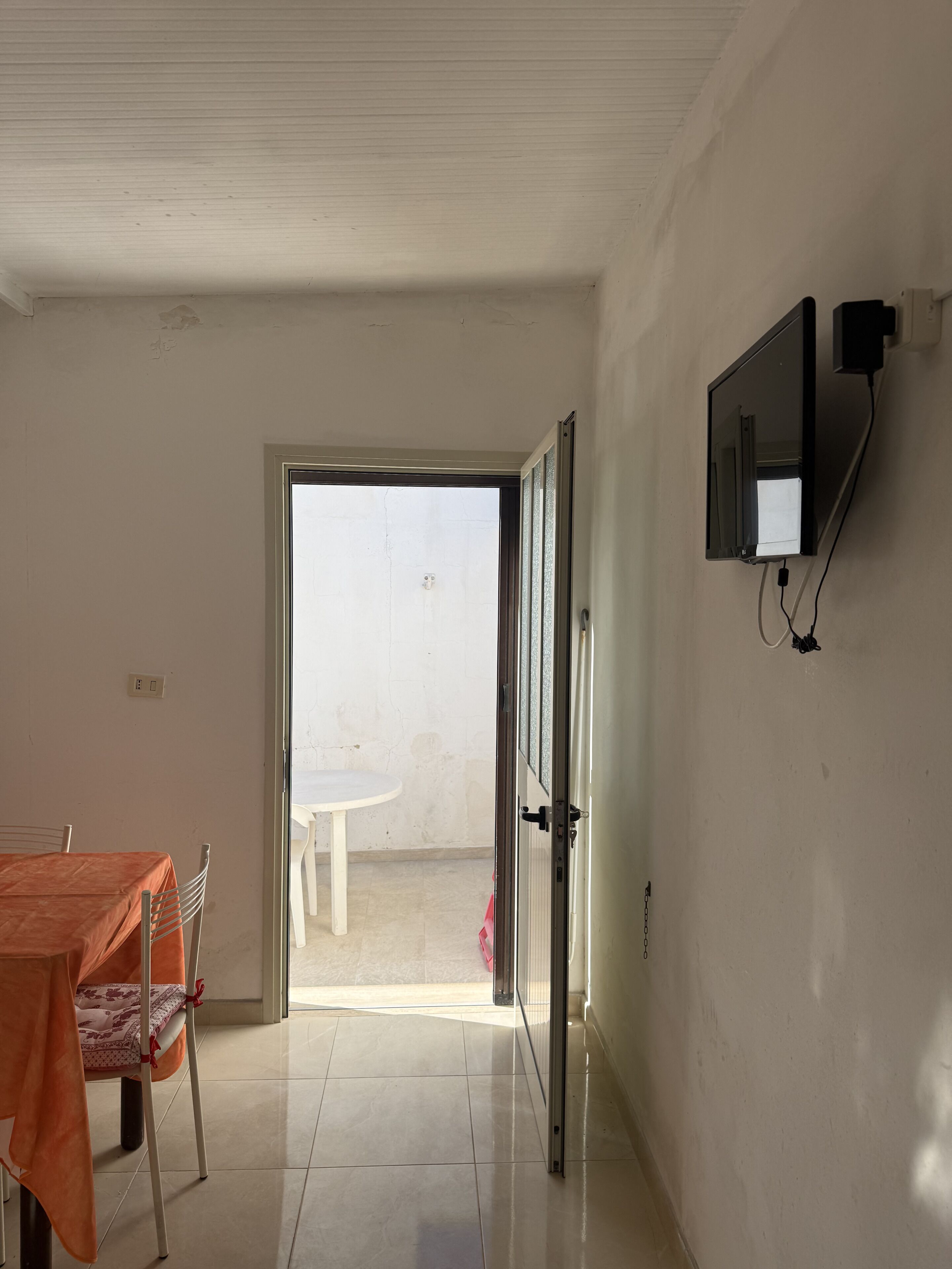 Ein offenes Durchgang zu einem Balkon mit einem weißen Tisch und Stühlen.