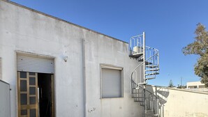 Un edificio con un'ampia porta aperta, una finestra chiusa e una scala a chiocciola.