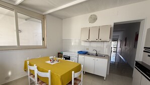 Una cucina compatta con tavolo, sedie, fornello e pensili.