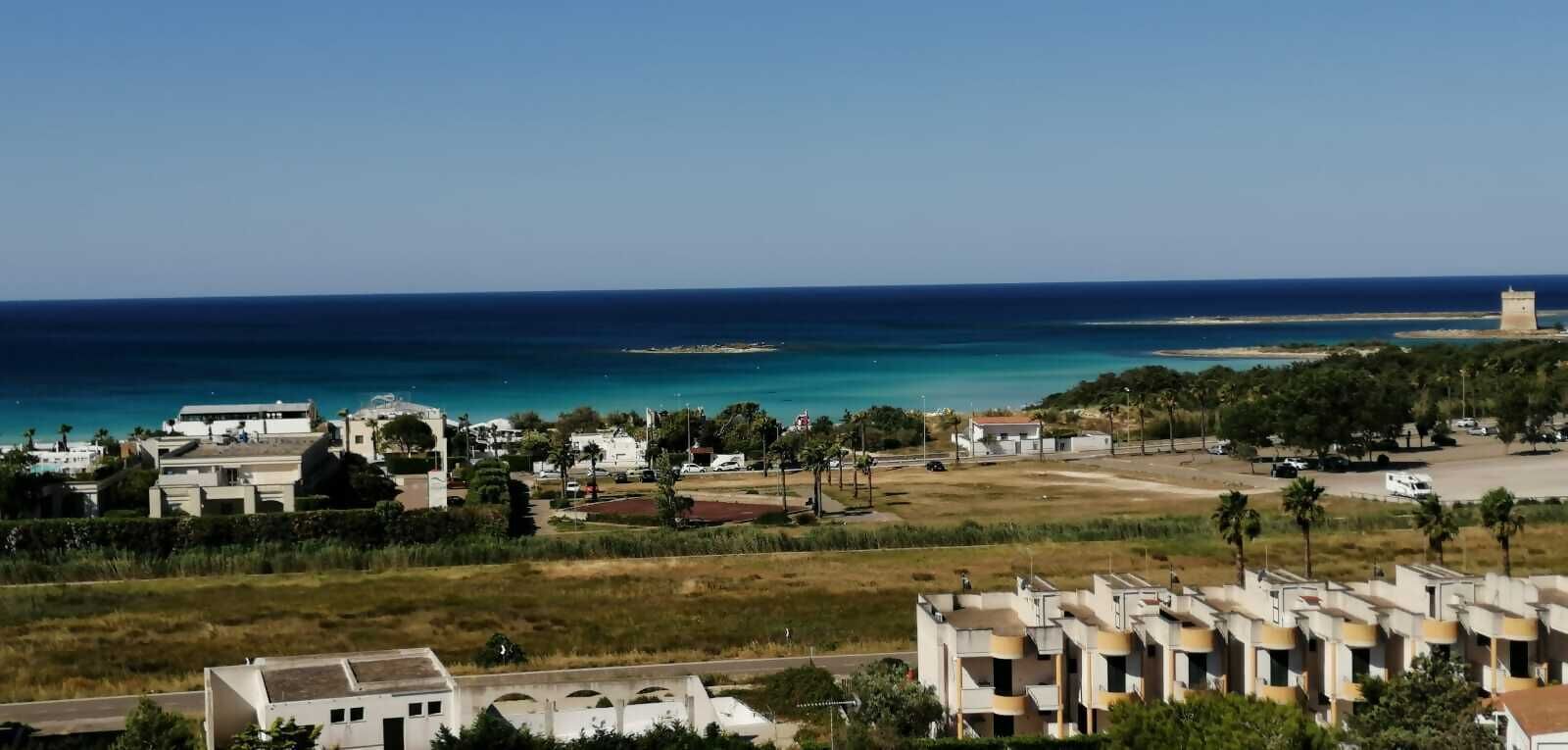 Zona residencial a la costa, amb edificis, una carretera i una vista clara del mar.