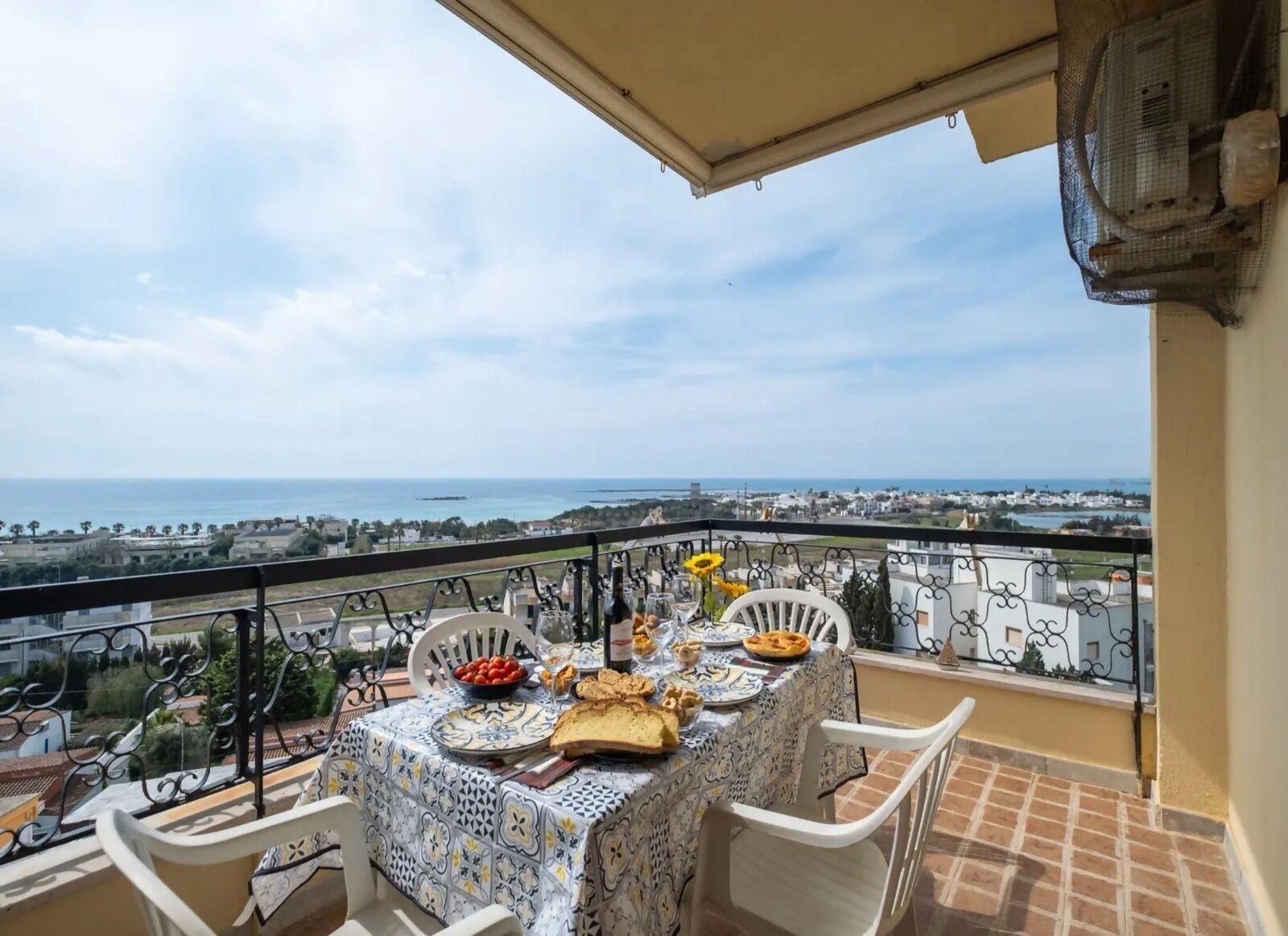 Un balcon avec une table dressée pour deux personnes, offrant une vue sur la côte.