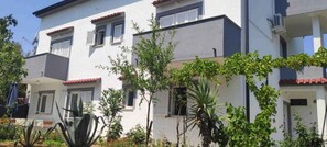 A multi-story residential building with balconies, a satellite dish, and various plants. - Holiday Apartment TWO-ROOM APARTMENT (Šilo)
