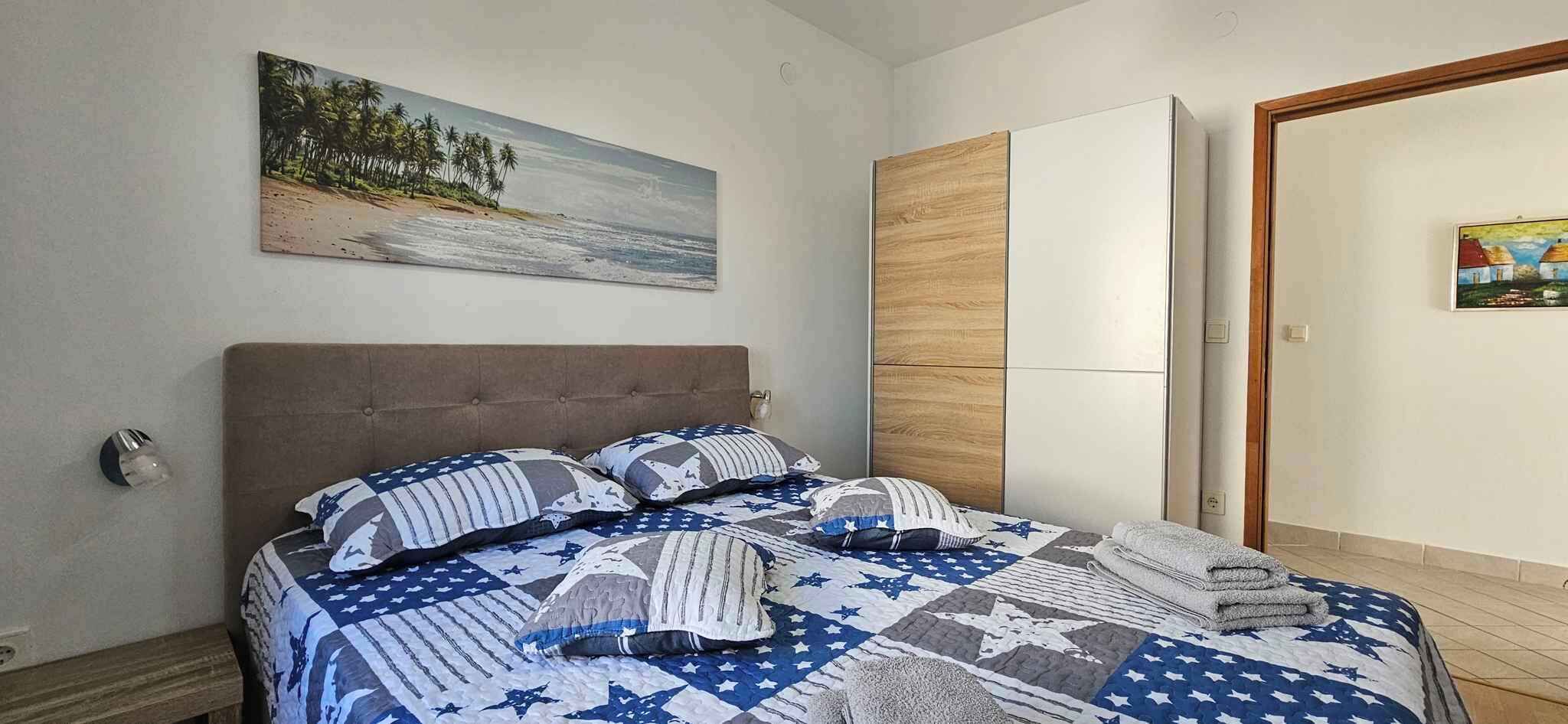 Une chambre à coucher avec un lit, un tableau, une armoire et une porte.