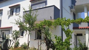 A multi-story residential building with balconies, a satellite dish, and various plants. - Holiday flat with balcony (Šilo)