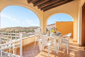 A balcony with a table and chairs, a view of a town, and a pergola structure. - Tavolara Sea View Apartments 2, San Teodoro, Italy (San Teodoro)