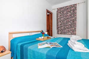 A neatly made bed with a blue bedspread, a tray with breakfast items, a book, and a pair of sunglasses on a nightstand. - Tavolara Sea View Apartments 1, San Teodoro, Italy (San Teodoro)