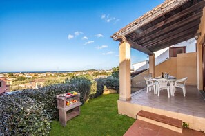 A patio with a table and chairs, a barbecue grill, and a view of the sea. - Tavolara Sea View Apartments 1, San Teodoro, Italy (San Teodoro)