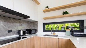 A modern kitchen with a large window, a built-in stove, and a coffee machine. - Aileen P3 V4 Saku Staycation (Sa Khu - Thalang)