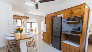 Eine Küche mit Holzausstattung, einem Edelstahlkühlschrank und einem Essbereich mit Tisch und Stühlen.