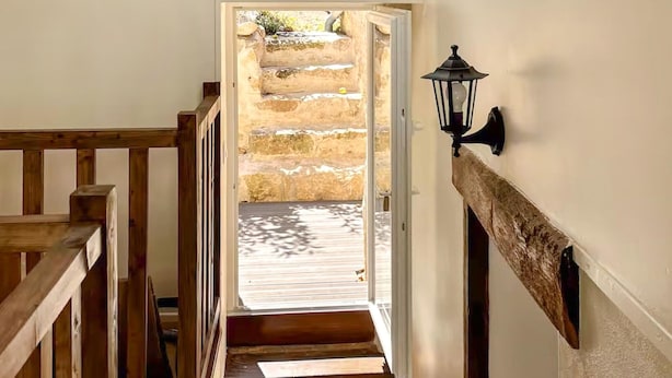 Eine Treppe führt zu einer Steinterrasse mit einer Laterne an der Wand.
