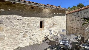 Ein Steinhaus mit einem kleinen Fenster, einem Metallstuhl und einem Tisch.