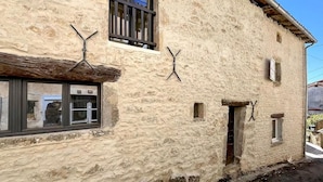Ein Steinhaus mit zwei Fenstern, einer Tür und einem kleinen Fenster an der Seite.