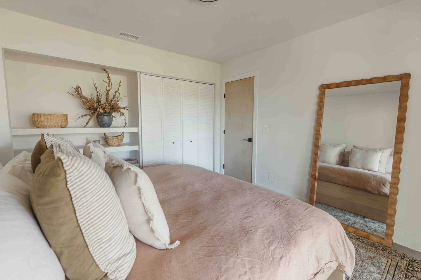 Ein Schlafzimmer mit einem Bett, einem Spiegel, einem Kleiderschrank und einem Regal mit Dekoration.