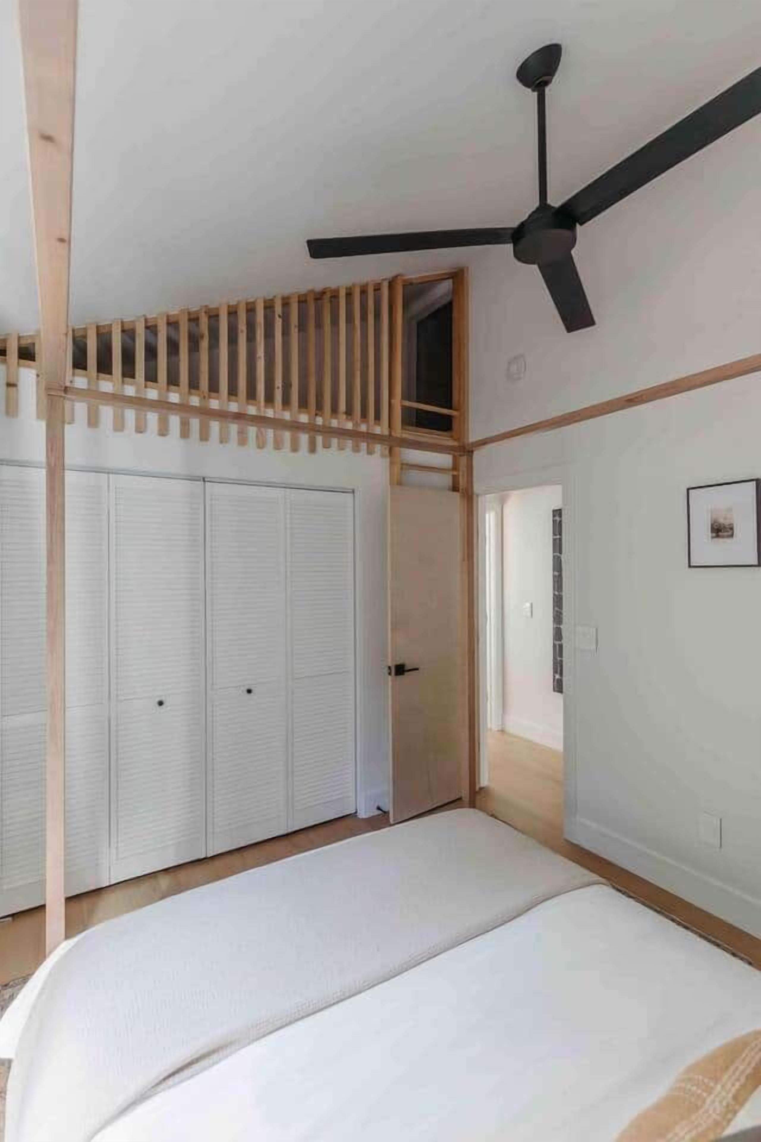 Un dormitorio con cama, ventilador de techo, techo de listones de madera y armario.
