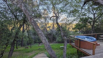 A hot tub on a wooden deck surrounded by trees.