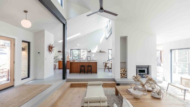 A spacious living area with a kitchen in the background, a fireplace, and a ceiling fan. - Skog Dom | Retreat in the Trees | Hot Tub | Auburn (Placer County)