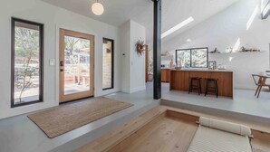 A modern interior with a kitchen island, bar stools, and a dining area. - Skog Dom | Retreat in the Trees | Hot Tub | Auburn (Placer County)