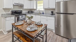 Una cocina con gabinetes blancos, un refrigerador de acero inoxidable, un microondas y una estufa.