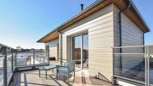 Ein modernes Gebäude mit Balkon, Glastüren und einem Holzdach.