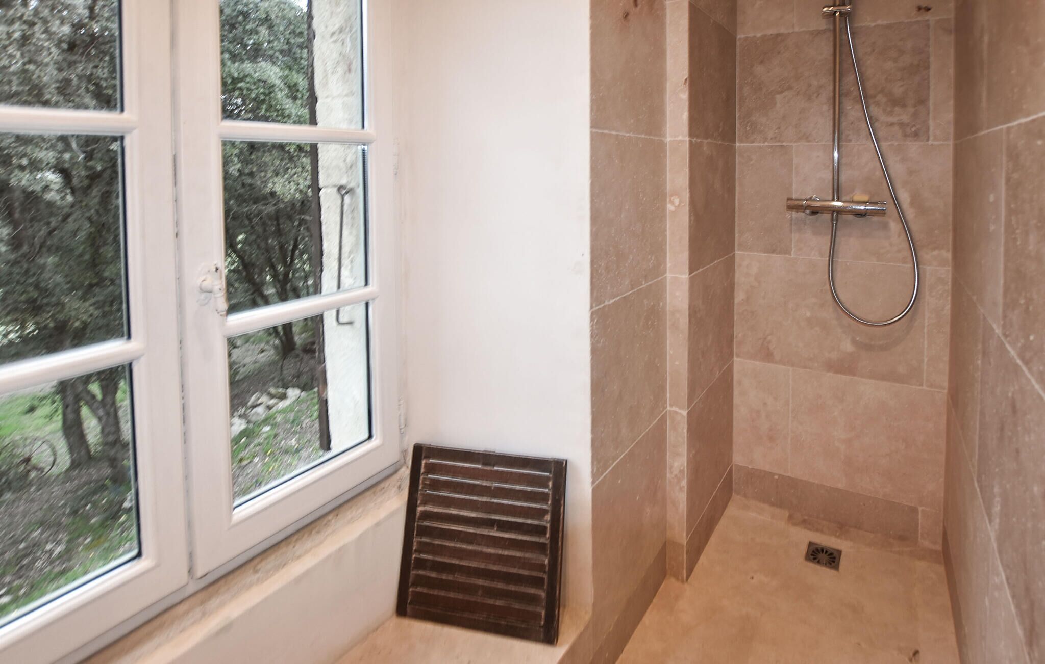 A bathroom with a shower, a window, and a vent.