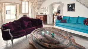A rustic living room with a stone ceiling, a purple sofa, a blue sofa, and a wooden coffee table. - Maison avec piscine privée (Clansayes)