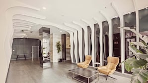 A modern lobby with a unique ceiling design, leather armchairs, a coffee table, and a staircase with a view. - Two Bedroom Unit in Central Adelaide (City of Adelaide)