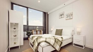 A modern bedroom with a bed, bedside tables, a wardrobe, and large windows. - Two Bedroom Unit in Central Adelaide (City of Adelaide)