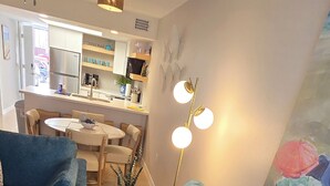 Een moderne woonkamer met een hoekbank, een eettafel en een keuken op de achtergrond.