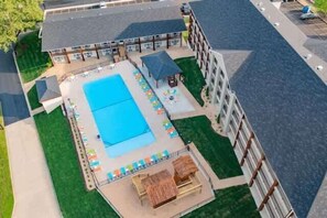 An aerial view of a hotel with a swimming pool, lounge chairs, and a covered seating area. - Creekside, walk to Landing and convention center (Branson)