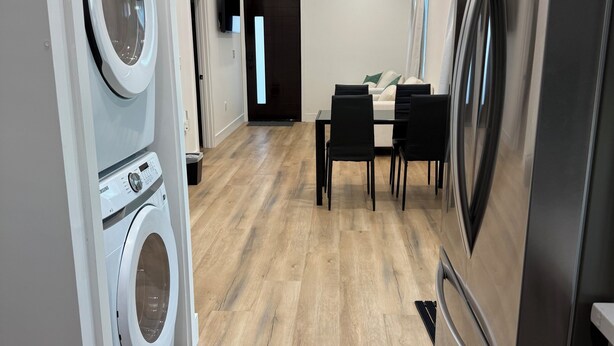 A modern kitchen with stainless steel appliances, a dining area with a table and chairs, and a laundry area with a washing machine. - Perfect 2-bedroom corporate apartment with AC in peaceful Altadena (Altadena)