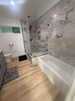 A modern bathroom with a glass-enclosed shower, a white bathtub, and a marble wall. - Perfect 2-bedroom corporate apartment with AC in peaceful Altadena (Altadena)