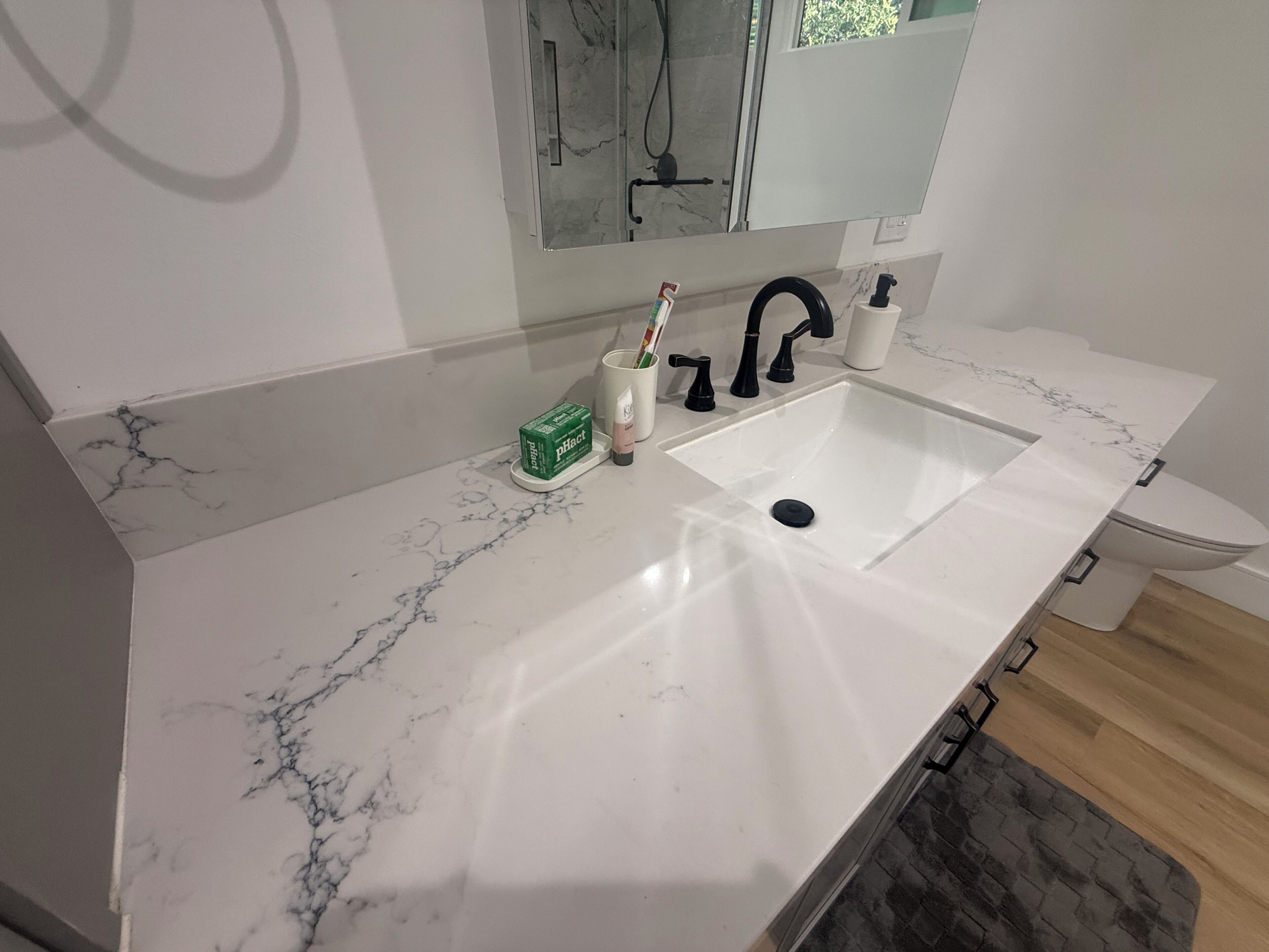 A bathroom with a white marble sink, black faucet, and a toilet.