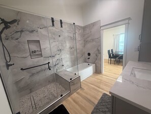 Un baño moderno con ducha de vidrio, bañera y pared de mármol.