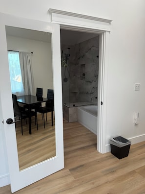 A modern bathroom with a glass-enclosed shower, marble walls, and a small shelf.