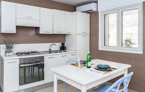 Eine moderne Küche mit weißen Schränken, einem Gasherd, einem Backofen und einem Fenster mit Blick.
